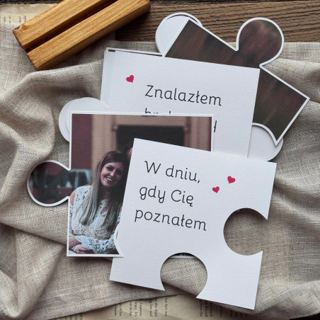 Kilka puzzli oraz drewienko z zestawu prezentowane na ozdobnym tle