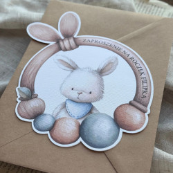 Zaproszenie Rino - w kształcie grzechotki z króliczkiem, położone na kraftowej kopercie