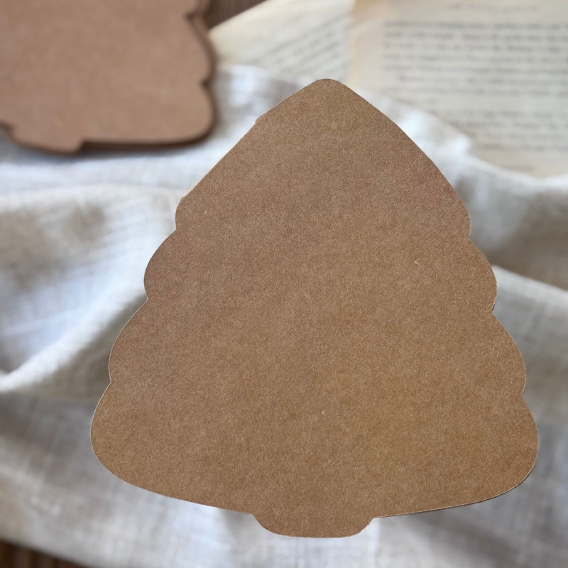 Baza kartki w kształcie choinki oraz wzorniki z papieru kraftowego, rozłożone na ozdobnym tle.