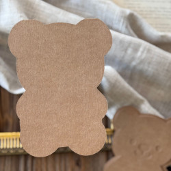 Baza kartki w kształcie misia oraz rozłożone wzorniki z papieru kraftowego na dekoracyjnym tle.