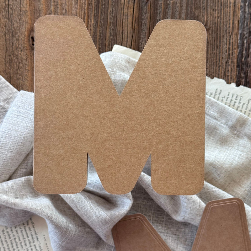 Baza do kartki handmade w kształcie litery T oraz papierowe wzorniki ułożone na ozdobnym tle.