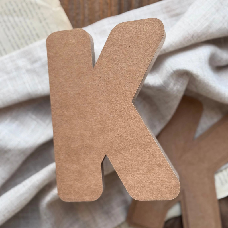 Baza do kartki handmade w kształcie litery K oraz papierowe wzorniki ułożone na ozdobnym tle.